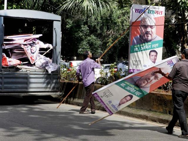 MCGM workers pull apart the banners of political parties in Bandra a day after the election code of conduct came into force for the upcoming assembly polls. (Kalpak Pathak/HT photo)