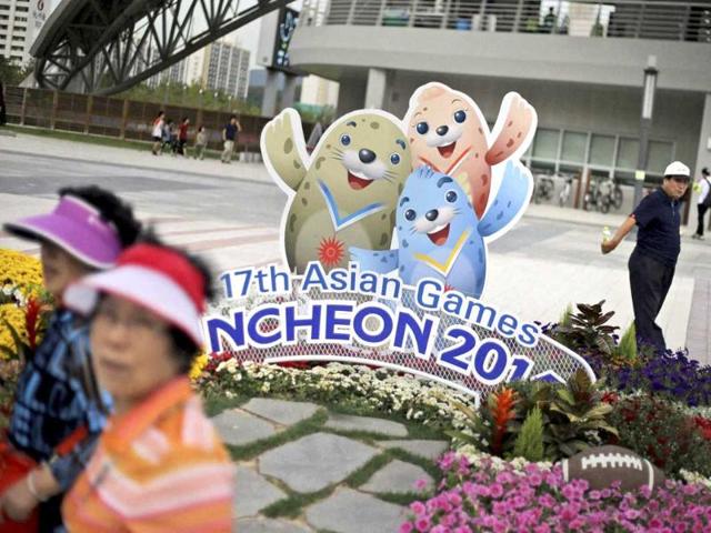 People walk past the cardboard cutouts of Barame, left, Vichuon, center, and Chumuro, the mascots of the 17th Asian Games, outside a stadium in Incheon. (AP Photo)