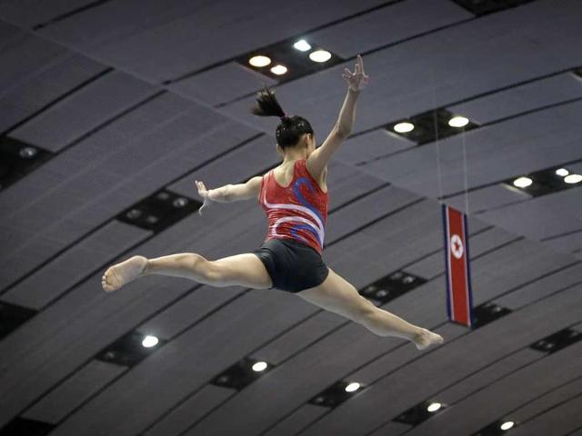 A gymnast practices her routine on the balance beam with the national flag of North Korea in the background.(AP Photo/Wong Maye-E)