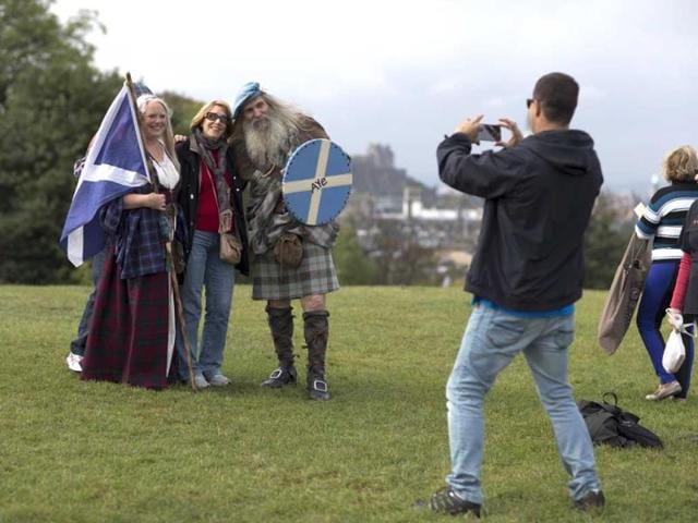 Scottish independence referendum Yes campaign supporters and members of a Scottish historical re-enactment group Ed Hastings, right, and his wife Sandy Hastings, left, wearing historical Scottish outfits pose for photographs for tourists on Calton Hill, in Edinburgh, Scotland. (AP photo)
