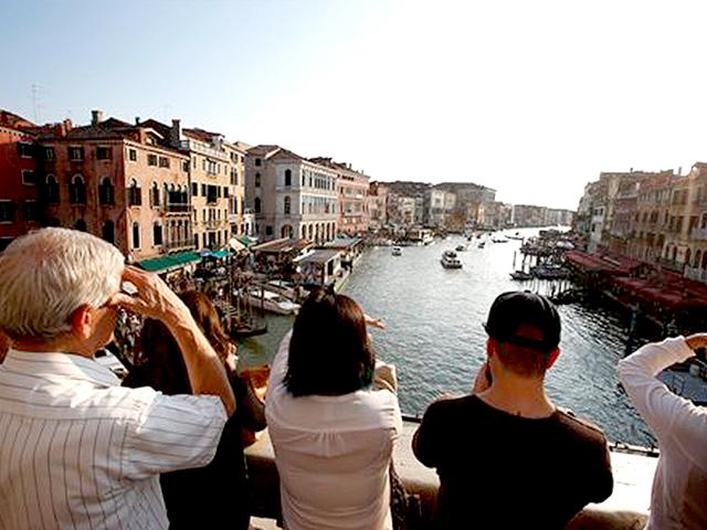 Tourists enjoy the view from the Rialto bridge in Venice, Italy. Venice city officials are closing a walkway fronting the picturesque Grand Canal on Monday to keep crowds away from George Clooney's wedding to Alamuddin. (AP)