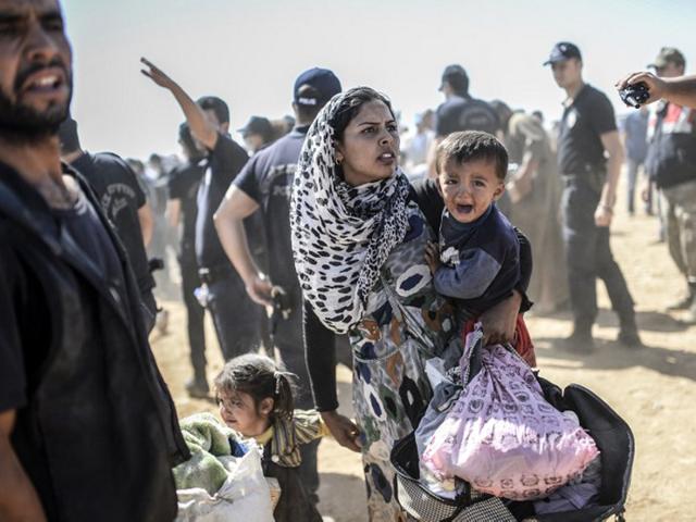 Turkey, Suruc: September 23, 2014 A Syrian Kurdish woman crosses the border between Syria and Turkey at the southeastern town of Suruc in Sanliurfa province. As many as 400,000 people may flee to Turkey from Syria's Kurdish region to escape attacks by the Islamic State group. (AFP)