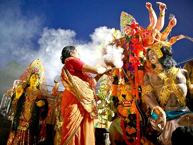 A Hindu devotee offers prayers before an idol of Goddess Durga, before immersing the same in the river Brahmaputra in Gauhati. (AP Photo/Anupam Nath)