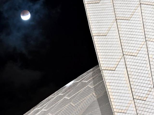 The moon is seen alongside the Sydney Opera House during a total lunar eclipse in Sydney . (AFP Photo)