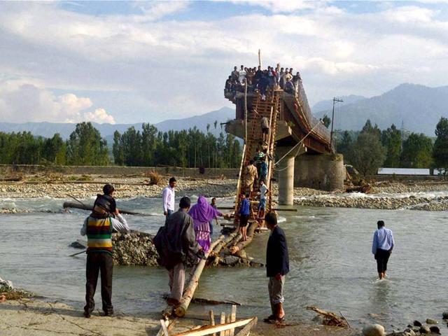 People use makeshift arrangements to climb bridge that was damaged by the recent floods in Kulgam district. (PTI Photo) 
