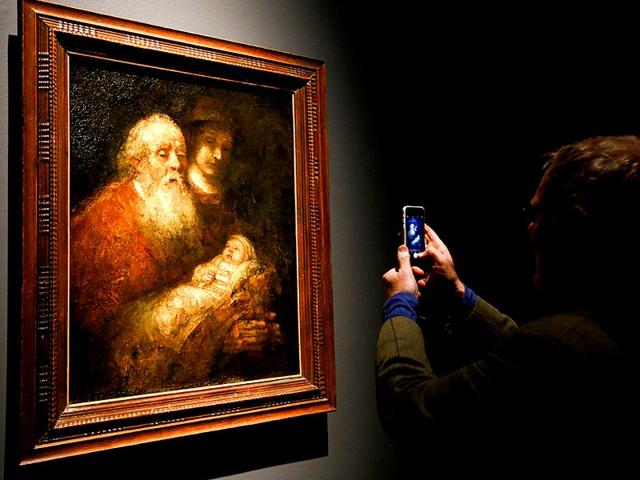 A man photographs Rembrandt's painting Simeon with the Infant Christ in the Temple about 1669, during a media event at The National Gallery in London. (AP Photo)