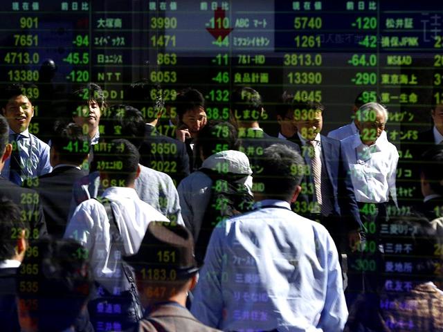 Pedestrians are reflected in an electronic board displaying various stock prices at a brokerage in Tokyo. (Reuters)