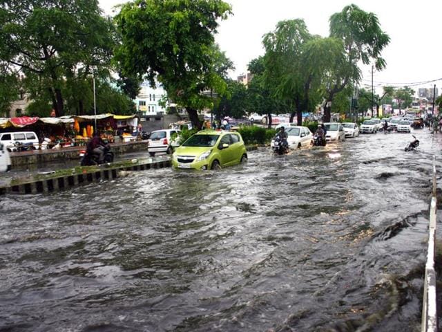 Commuters wade through a waterlogged road near Jyoti Talkies in Bhopal on Saturday after heavy rain lashed the city. (Praveen Bajpai/HT photo)
