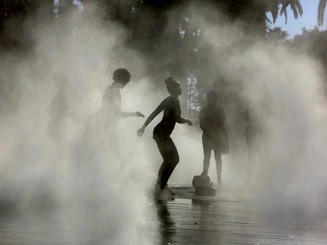 A woman dances in a mist fountain during an unusually warm and sunny autumn day in Nice. (Reuters)
