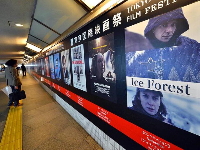 This picture taken on October 22, 2014 shows a pedestrian looking at posters of movies which will be screening at the Tokyo International Film Festival in Tokyo. Tokyo International Film Festival opens on October 23 with the focus heavily on Japanese animated movies and with cult superhero Ultraman set to swoosh down the red carpet with Prime Minister Shinzo Abe. (AFP) 