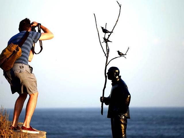 A man takes a picture of a sculpture by artist Wang Shugang of China titled "Man playing with birds" at Bondi beach in Sydney. (AFP Photo)