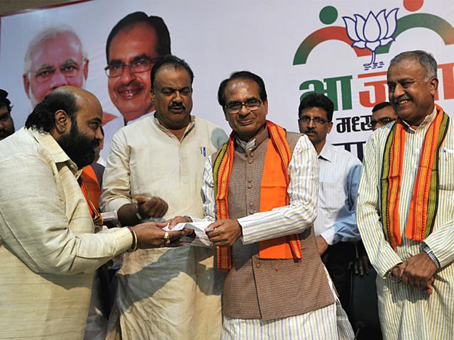 Chief-minister-Shivraj-Singh-Chouhan-hands-over-BJP-membership-slip-to-Congress-workers-after-they-joined-the-BJP-at-the-party-office-in-Bhopal-Mujeeb-Faruqui-HT-photo