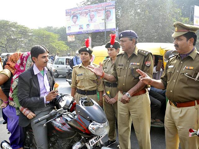 NCC Cadets offering flowers to drivers found not wearing helmets and flouting safety rules at Hapur Chungi, in Ghaziabad. (Sakib Ali/ Hindustan Times)
