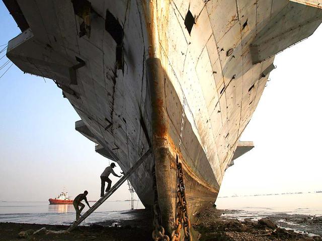 Workers climb to enter India's first aircraft carrier INS Vikrant to dismantle it at a ship-breaking yard in Mumbai. (PTI photo)