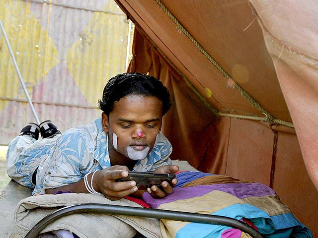 An artist uses his mobile phone backstage, right before his performance at the Apollo Circus in Noida. (Burhaan Kinu/HT Photo)