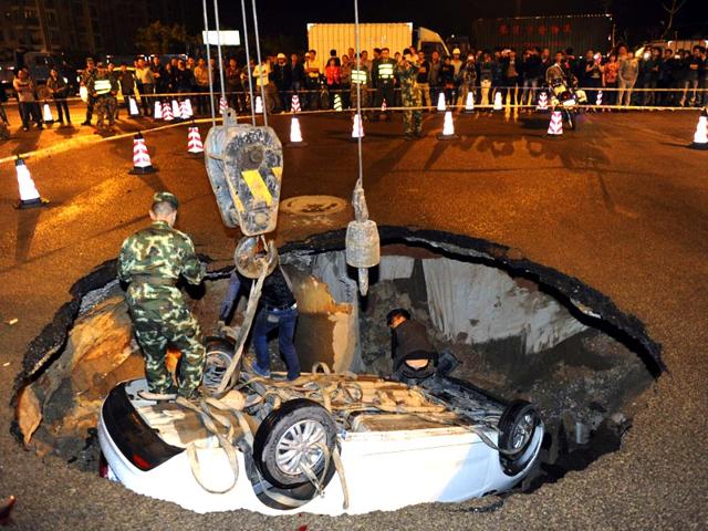 People try to pull out a car which was stuck after a road caved-in in Quanzhou, Fujian province. (Reuters Photo)