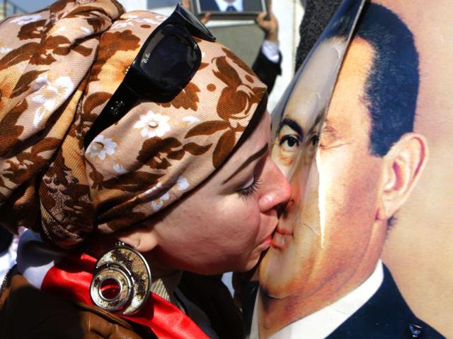 A supporter of former Egyptian President Hosni Mubarak kisses his poster following his verdict outside Maadi Military Hospital in Cairo, Egypt. (AP Photo)