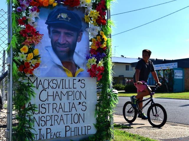 A boy rides his bicycle next to a portrait of the late Australian cricketer Phillip Hughes in Macksville. (AFP Photo)
