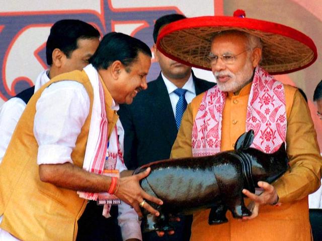 Prime Minister Narendra Modi being felicitated with traditional Assamese Japi, Gamocha and wooden one horned rhino in Guwahati. (PTI Photo)