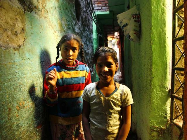 Sonia, a special needs child, stands in a narrow alley along with her sister Mantoo (R) near her house where she stays with her grandparents in a slum in Govindpuri area of Delhi on World Disabled Day. (Gurinder Osan/HT Photo)