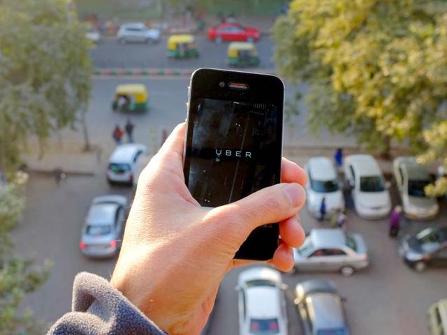 The-Uber-smartphone-app-used-to-book-taxis-using-its-service-is-pictured-over-a-parking-lot-AFP-photo
