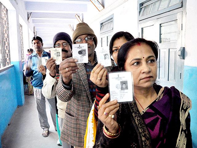 People show their voter cards as they stand in queue to cast their votes in the third phase of Jharkhand assembly elections in Ranchi. (PTI photo)
