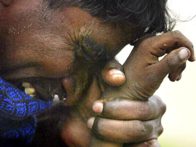 An Indian man cries as he holds the hand of his eight-year-old son who was killed in the tsunami in Madras, in December 2004. (Reuters)