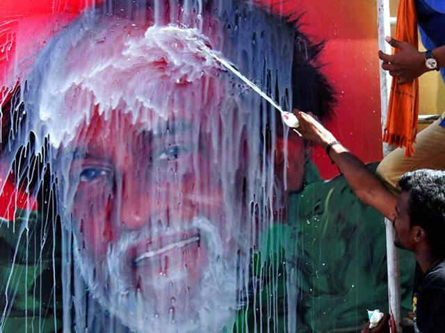 Fans pour milk on Rajnikanth's poster during the release of his movie "Lingaa" on his 64th birthday in Chennai . PTI Photo by R Senthil Kumar 