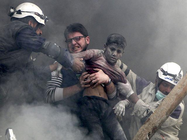 Men rescue a boy from under the rubble after what activists said were explosive barrels were dropped by forces loyal to Syria's President Bashar Al-Assad in the Al-Shaar neighbourhood of Aleppo. (Reuters Photo)