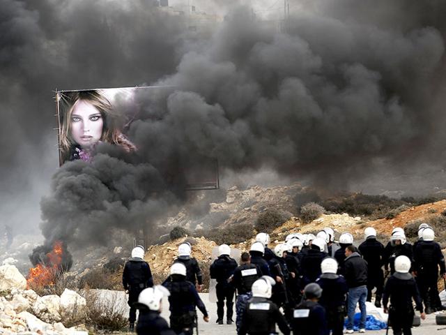 Palestinian policemen stand near burning tyres set ablaze by demonstrators outside Jalazoun refugee camp near the West Bank city of Ramallah. (Reuters Photo)
