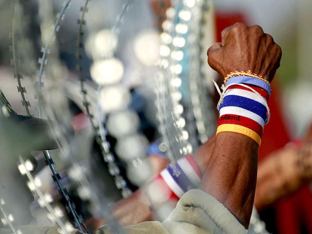 Anti-government protesters chant slogans next to a line of barbed wire during a rally outside the Center for Maintaining Peace and Order (CMPO) on the outskirts of Bangkok, Thailand. (AP Photo)