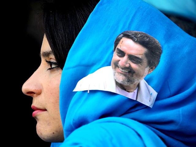 An Afghan woman with a portrait of presidential candidate Abdullah Abdullah on her scarf listens to his speech during a campaign rally at a stadium in the northwestern city of Herat. (AFP Photo)