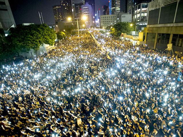 Protestors and student demonstrators hold up their cellphones in a display of solidarity during a protest outside the headquarters of Legislative Council in Hong Kong. (AFP Photo)