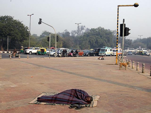 Life in the metro goes on unaware of the condition the homeless face in the capital. A man catches up on his sleep on a pavement near Nizamuddin, in south Delhi, as life goes on in the city. (Subrata Biswas/HT Photo)