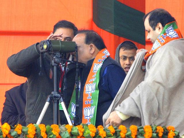 Union minister of Science and Technology Harsh Vardhan looks through the binoculars as Member of Parliament Mahesh Giri and Parvesh Verma wait for their turn during the BJP rally at Ramlila Maidan in New Delhi. (HT photo/Sonu Mehtal)