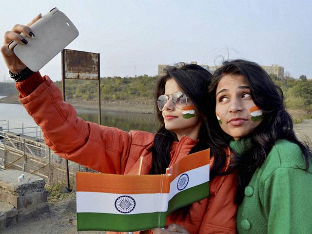 Young girls take a selfie with national flags as they gear up for Republic Day celebrations in Bhopal on Tuesday. (PTI photo)