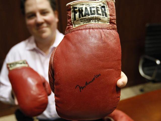 Chris Ivy, director of sports auctions at Heritage Auctions, holds the autographed gloves of Ali and Liston. There have been many theories about what exactly happened: Did Liston, an ex-con known as the Big Bear, throw the fight because he was in debt to the mob? Or did Ali actually deliver a perfectly landed punch? (Text and Photo: AP) Chris Ivy, director of sports auctions at Heritage Auctions, holds the autographed gloves of Ali and Liston. There have been many theories about what exactly happened: Did Liston, an ex-con known as the Big Bear, throw the fight because he was in debt to the mob? Or did Ali actually deliver a perfectly landed punch? (Text and Photo: AP)