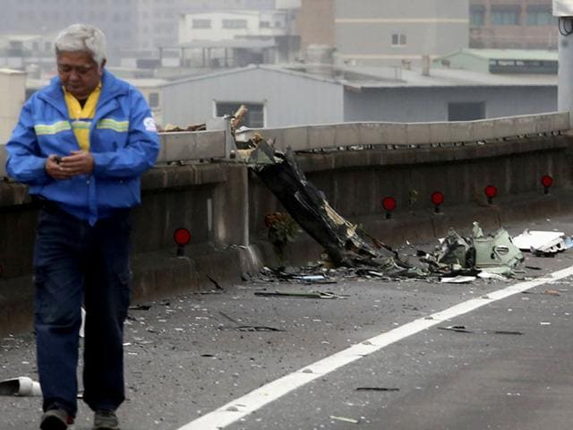 A man walks past next to the wreckage of a TransAsia Airways plane which hit a motorway before crash landing in a river, in New Taipei City. (Reuters)