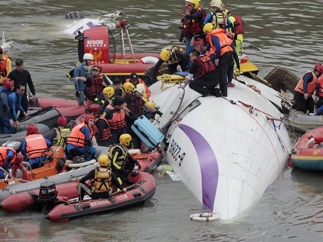 Emergency personnel try to extract passengers from the plane. (AP Photo)