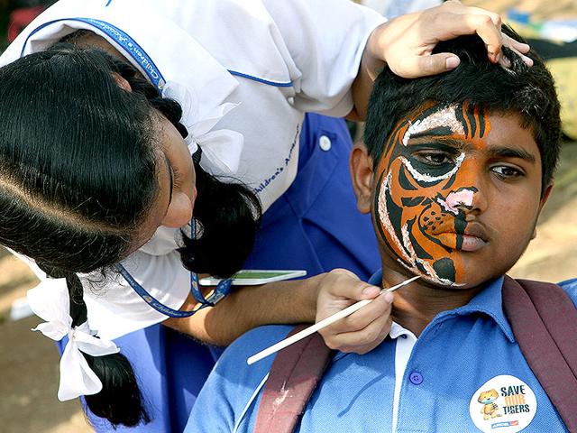 A girl paints tiger stripes on her friend's face during the 'Kids for Tiger' festival, a commitment to tiger conservation, at Maharashtra Nature Park in Mumbai. (Arijit Sen/HT photo)