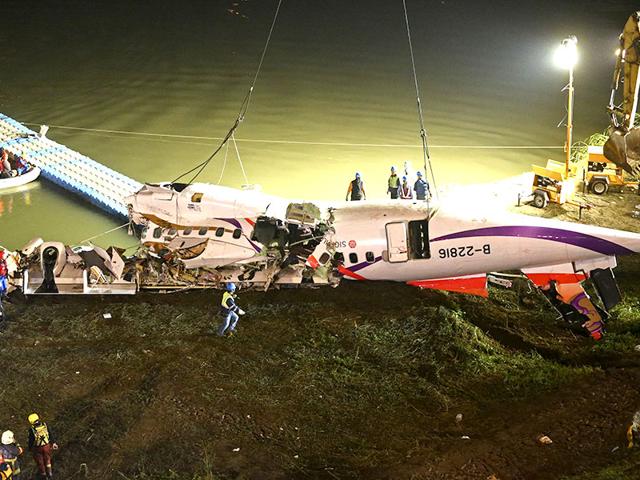The mangled fuselage of a TransAsia Airways commercial plane is dragged to the river bank. (AP Photo)