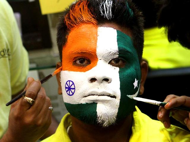 World Cup is nearing and Mumbai is gripped with cricket fever. School kids watch as a cricket fan gets the Indian Tricolour painted on his head. (Arijit Sen/HT photo)
