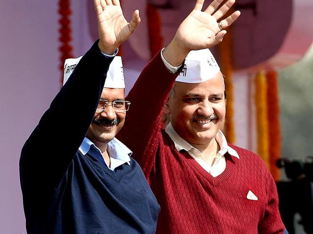 Chief minister Arvind Kejriwal (L) and Deputy CM Manish Sisodia greet supporters during the swearing-in ceremony at Ramlila Maidan in New Delhi. (AFP PHOTO)