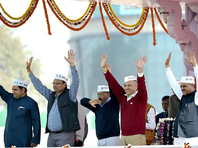 Delhi CM Arvind Kejriwal (C) and fellow AAP ministers Sandeep Kumar, (L), Asim Ahmed Khan (2L), Satyendra Jain (3L), Gopal Rai, (3R), Manish Sisodia (2R) and Jitender Singh Tomar (R) greet supporters during the swearing-in ceremony at Ramlila Maidan. (AFP PHOTO)