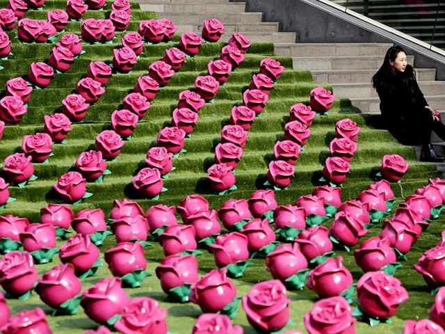 A woman poses for photographs next to an installation art work of roses at a shopping center on Valentine's Day, in Beijing. (Reuters)