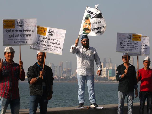 Aam Aadmi Party supporters hold placards and flags as they celebrate their leader Arvind Kejriwal's swearing-in ceremony as Delhi chief minister, at Marine Drive in Mumbai.(Kunal Patil/HT photo)