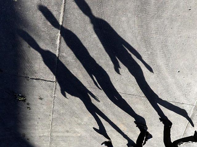 People walk as their long shadows fall on the road at Andheri in Mumbai. (Pratham Gokhale/HT Photo)