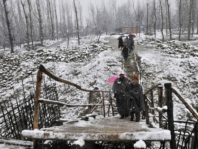 Men walking on a temperary foot bridge during snow falls.Wasim Andrabi.HT
