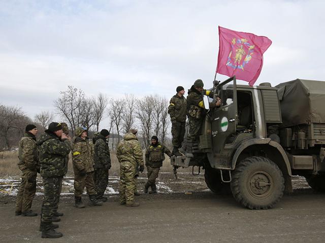 A-serviceman-fixes-a-flag-bearing-the-coat-of-arms-of-his-military-unit-on-a-truck-as-a-column-of-Ukrainian-forces-leave-Debaltseve-AFP-photo