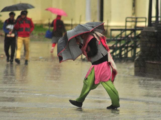 A woman braving strong wind and rain at Ridge in Shimla. Santosh Rawat/HT